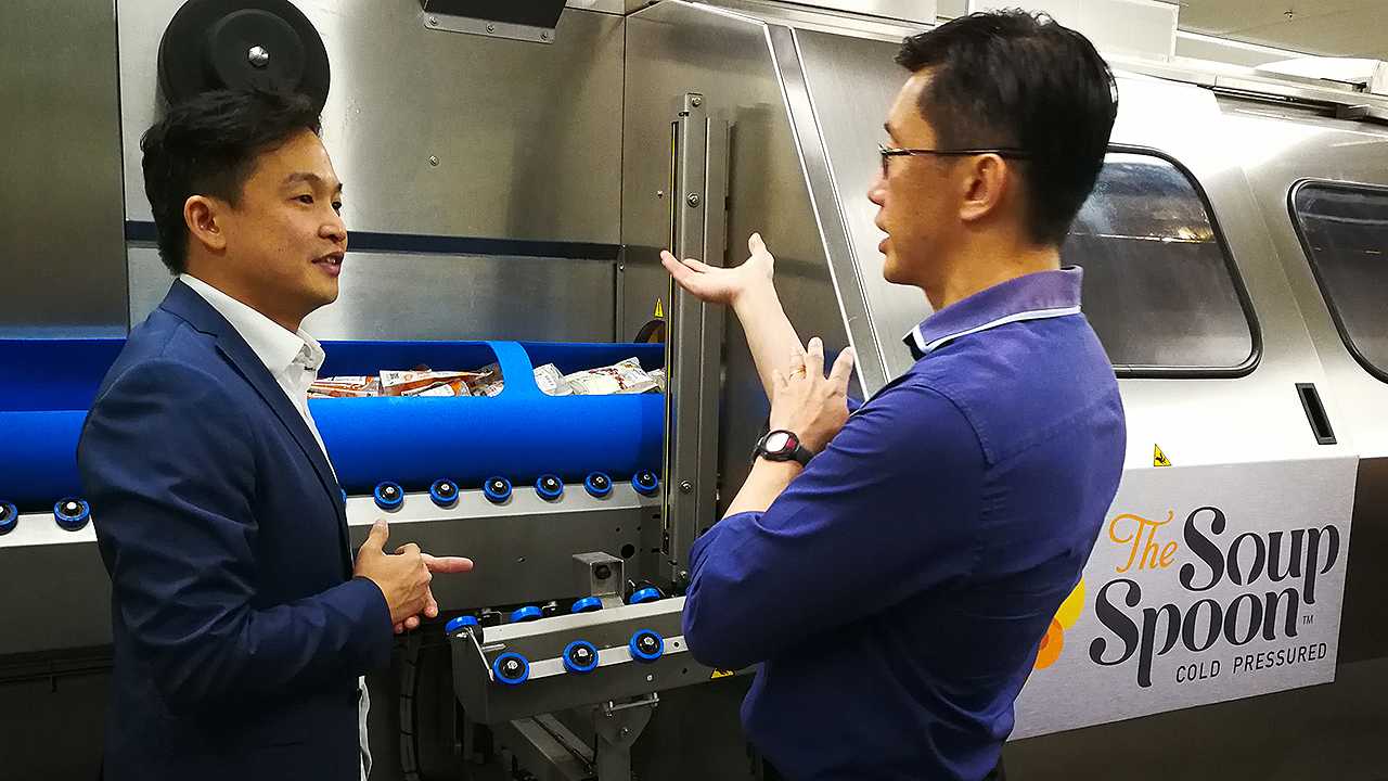 Managing Director of The Soup Spoon Andrew Chan demonstrating to Minister of State for Manpower Teo Ser Luck and attendees from the F&B industry how the HPP equipment works during a tour. (Photo: NTUC ThisWeek)