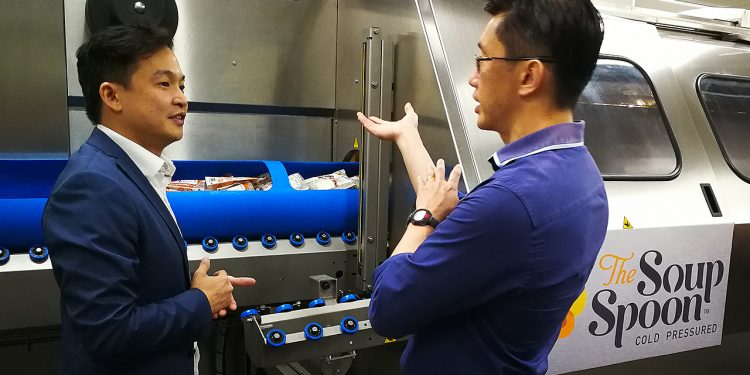 Managing Director of The Soup Spoon Andrew Chan demonstrating to Minister of State for Manpower Teo Ser Luck and attendees from the F&B industry how the HPP equipment works during a tour. (Photo: NTUC ThisWeek)