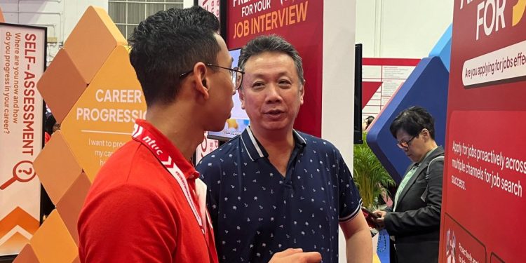 Two men talking in front of a poster.