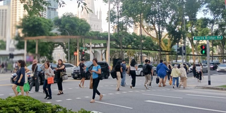 A group of people crossing the street at North Bridge Road in Singapore