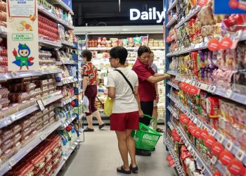 Shoppers browsing at an NTUC FairPrice outlet, where digital vouchers, housebrand items, and weekly promotions help stretch every dollar.