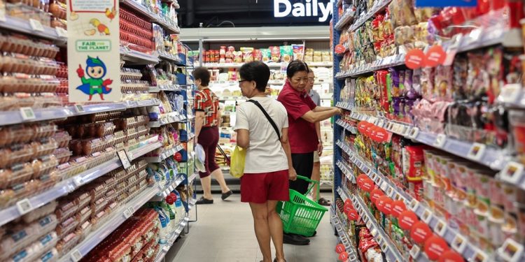 Shoppers browsing at an NTUC FairPrice outlet, where digital vouchers, housebrand items, and weekly promotions help stretch every dollar.