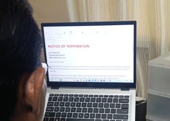 A man looking at a computer screen that says termination letter.