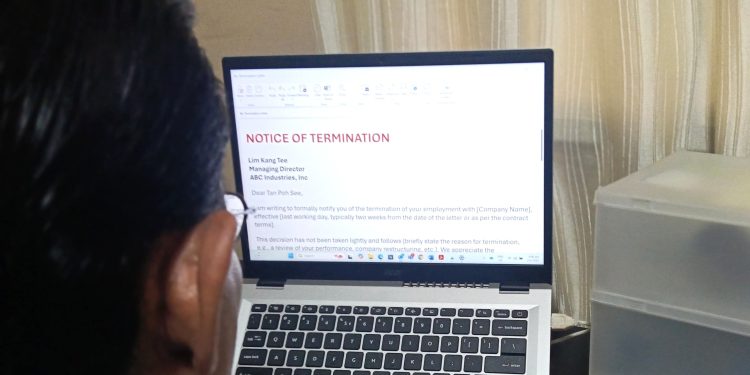 A man looking at a computer screen that says termination letter.