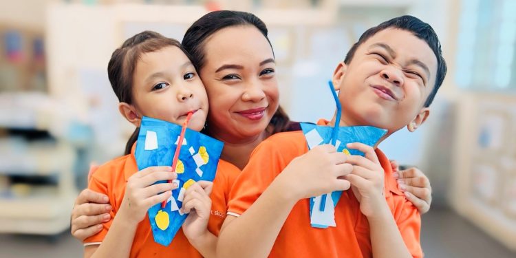 Aishah Mahzan with her children Hizsyafiyah and Hisziqri displaying their artwork from Bright Horizons Fund art classes at My First Skool