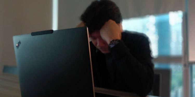 A distressed victim of age discrimination sitting at a desk with a laptop.